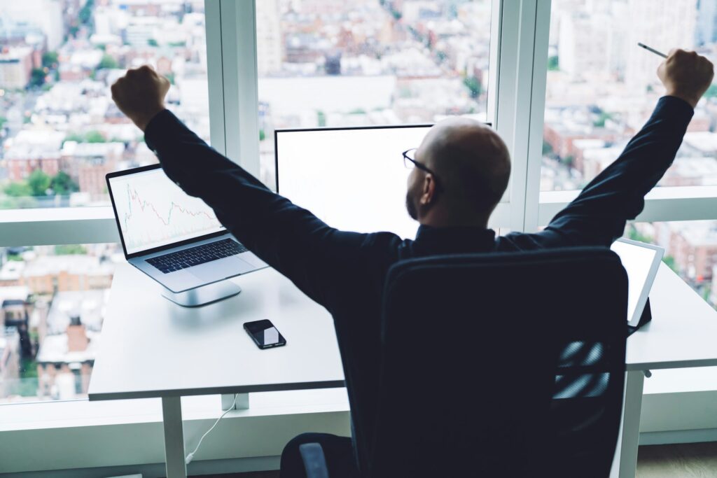 Man celebrating success on stock trading in office